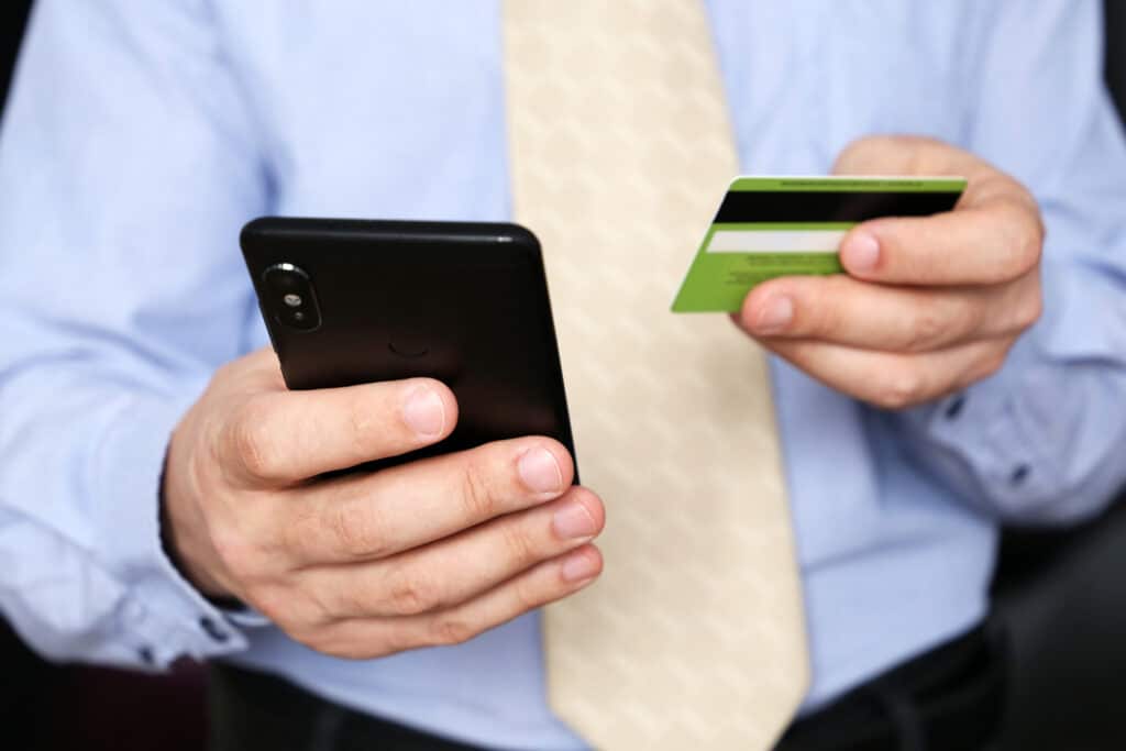 Man in office clothes holding credit bank card and smartphone in hands